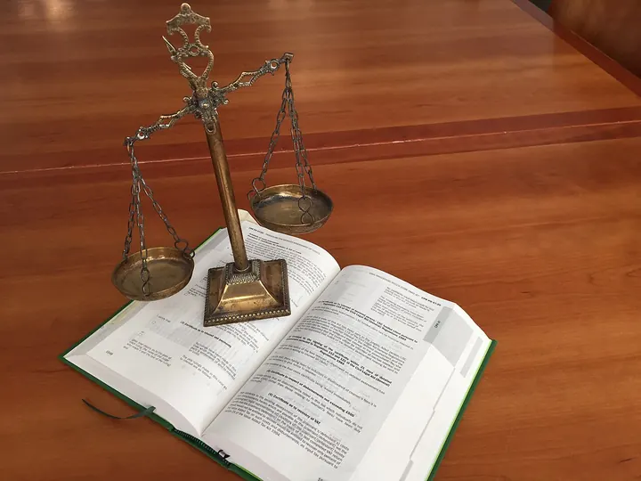 Латунные весы стоят на раскрытой книге на полированном деревянном столе